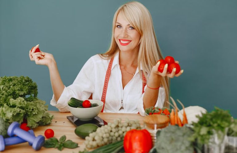 Healthy lifestyle concept with woman holding tomatoes and surrounded by fresh vegetables in a studio setting.