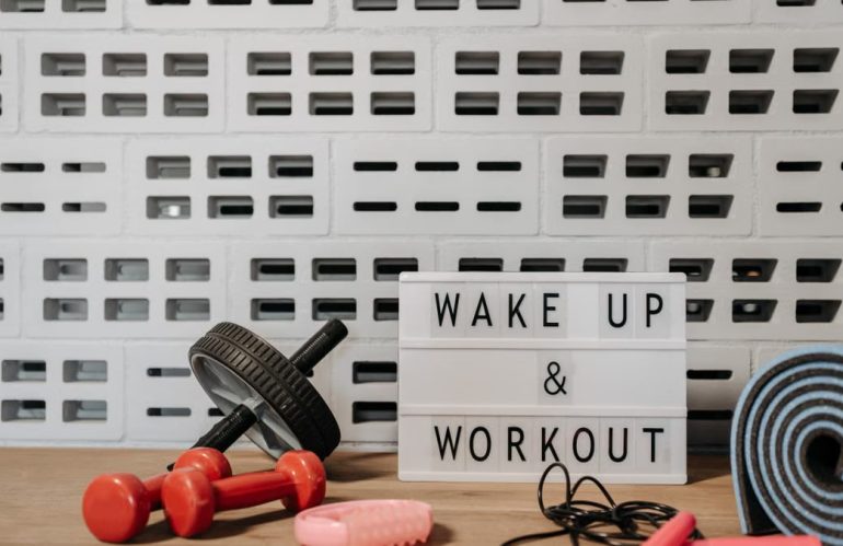 Fitness gear and motivational sign in home gym setup against a brick wall.